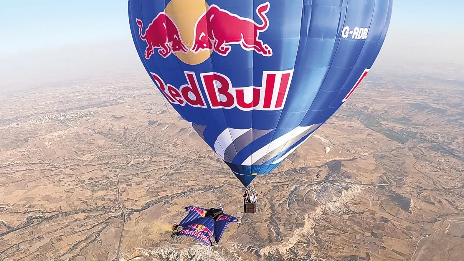 Wingsuit-atleten vliegen tussen heteluchtballonnen boven Cappadocië